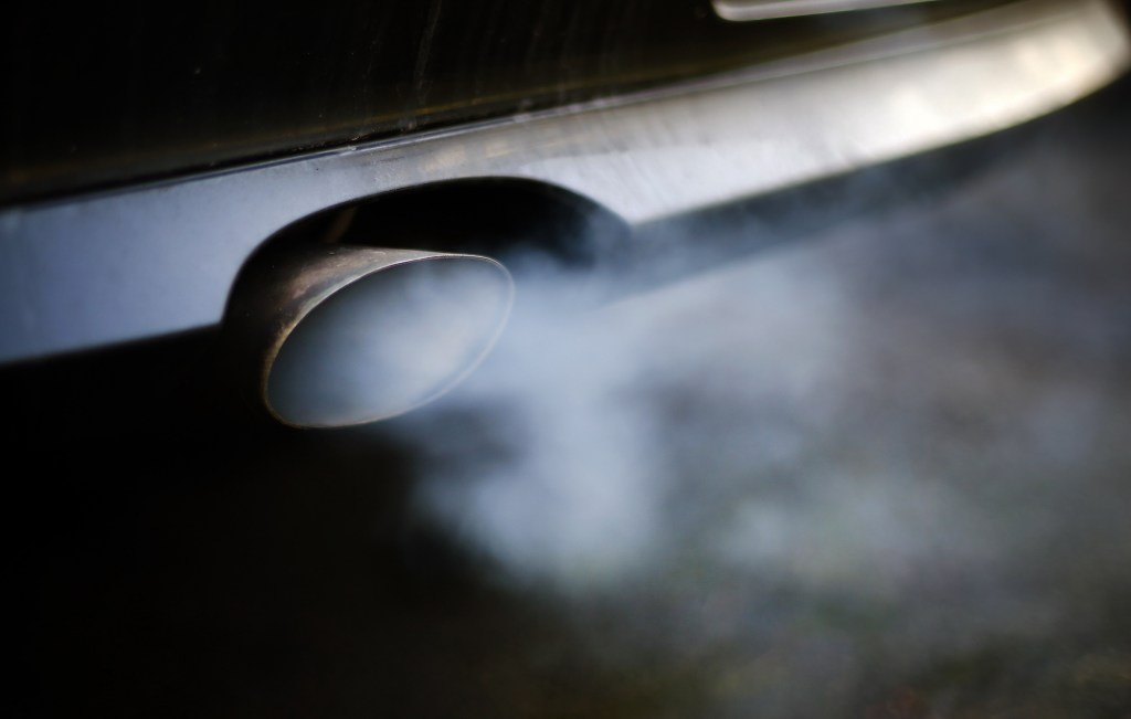 A car exhaust pipe emits smoke and carbon monoxide