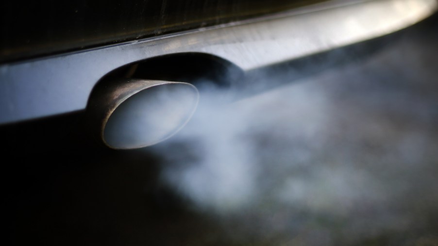 A car exhaust pipe emits smoke and carbon monoxide