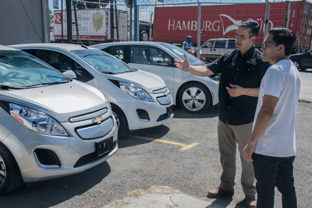 A car salesperson shows a customer the car lot.