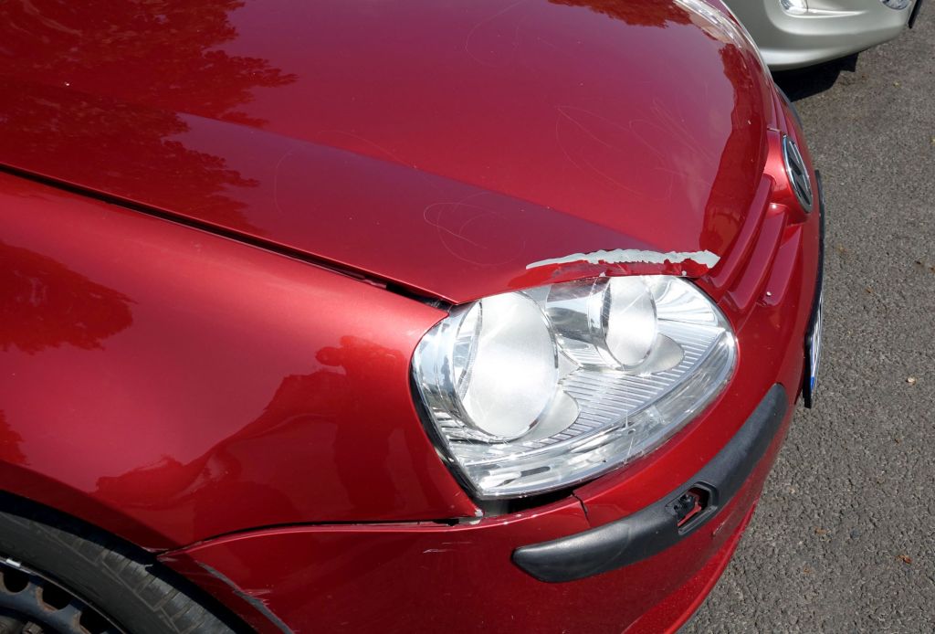 A Volkswagen car with red paint damage above the headlight