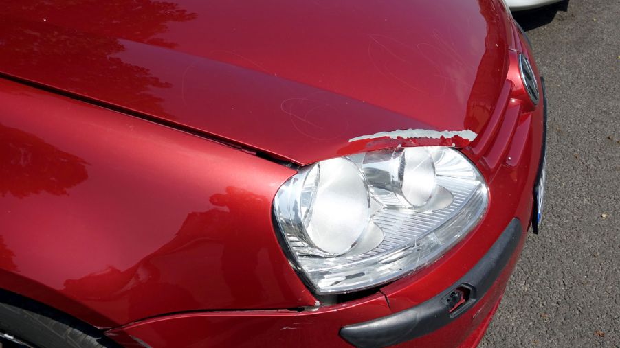 A Volkswagen car with red paint damage above the headlight