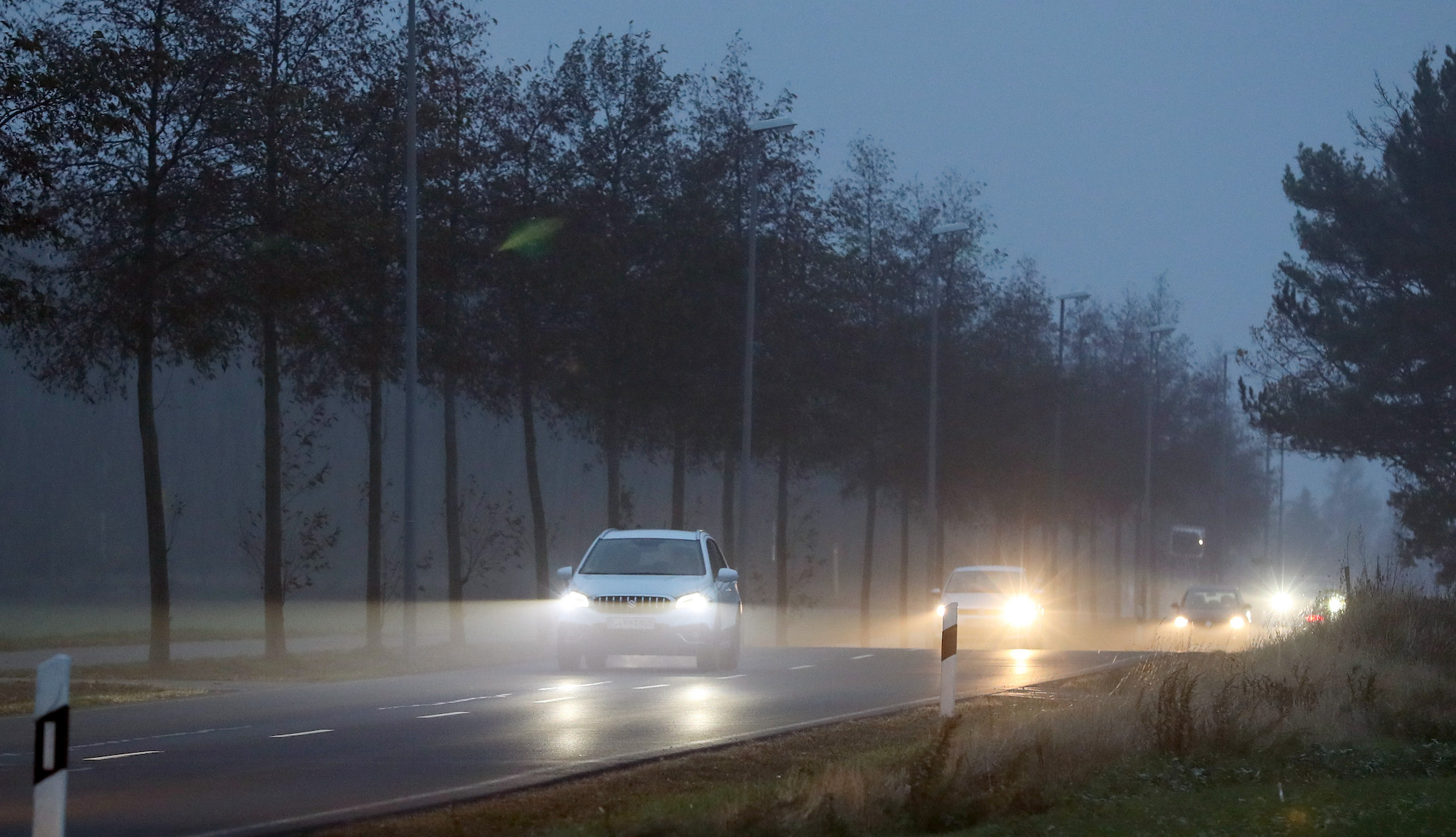 Cars with their headlights on drive on a cloudy morning in November 2018