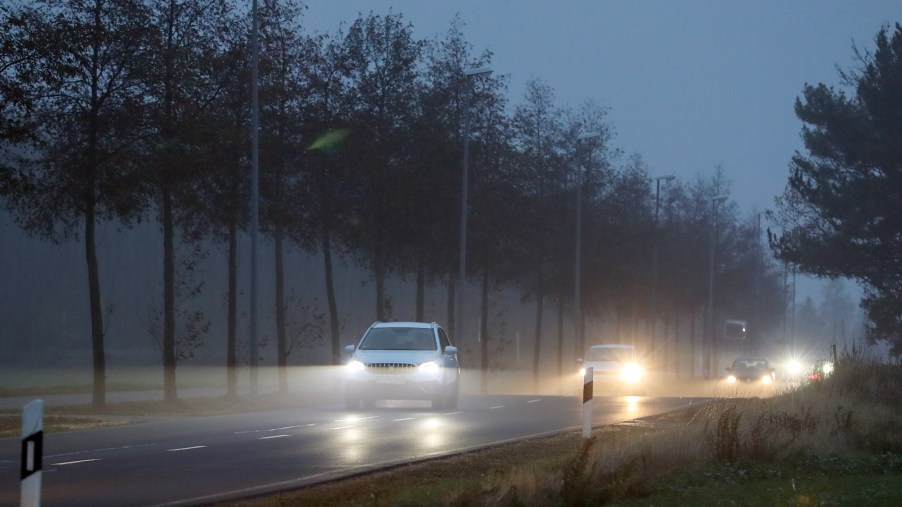 Cars with their headlights on drive on a cloudy morning in November 2018