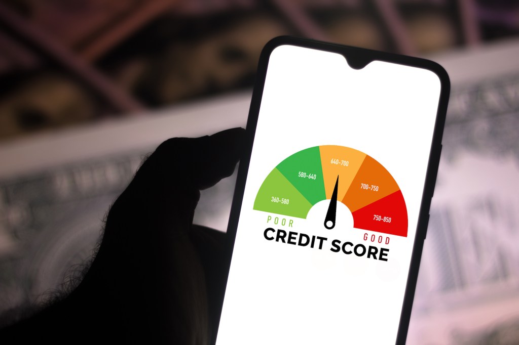 In this photo illustration, a businessman holds his smartphone showing a graph with the credit score.