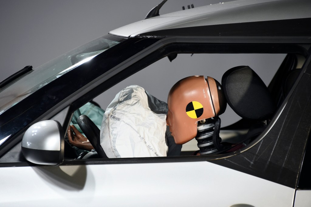 A car and its airbag are pictured after a frontal crash test with another car.