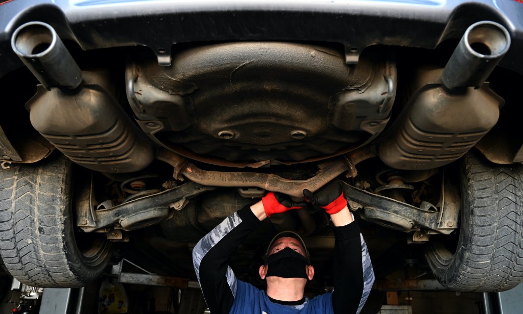 A mechanic wearing a protective face mask repairs a car