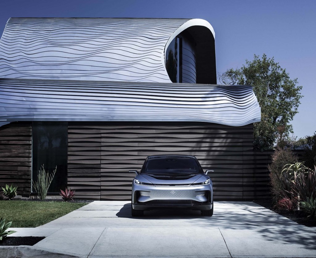 A silver 2021 Faraday FF 91 parked in front of a garage.