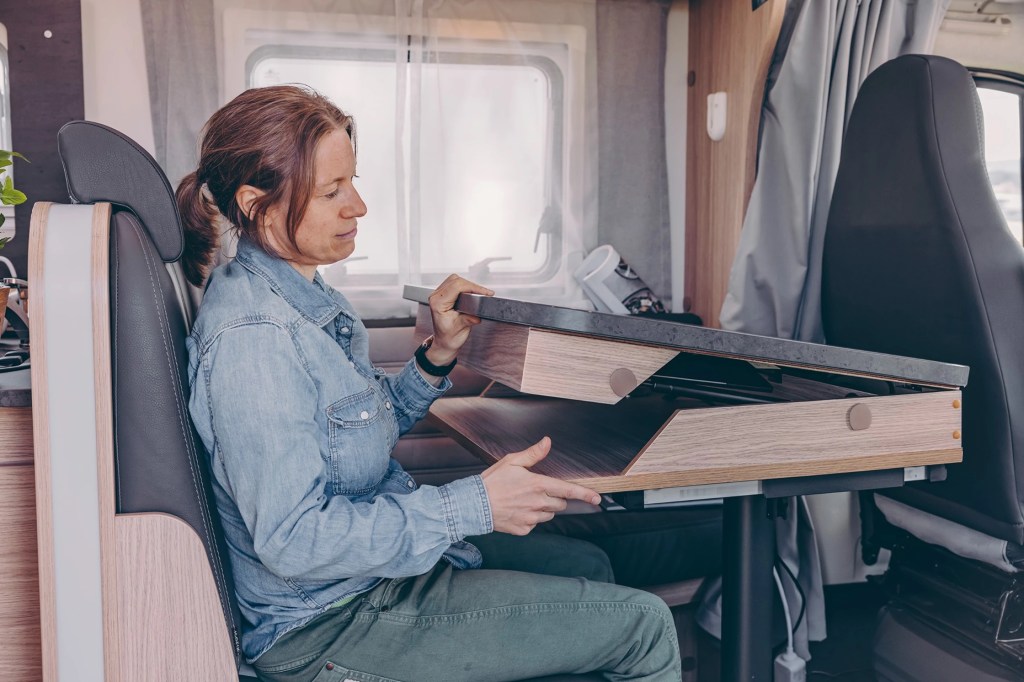 Lady opening up the modular desk that makes the Sunlight Camper the ultimate work remote setup