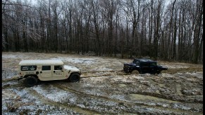 A beige H1 hummer winches a black H1 tug-of-war