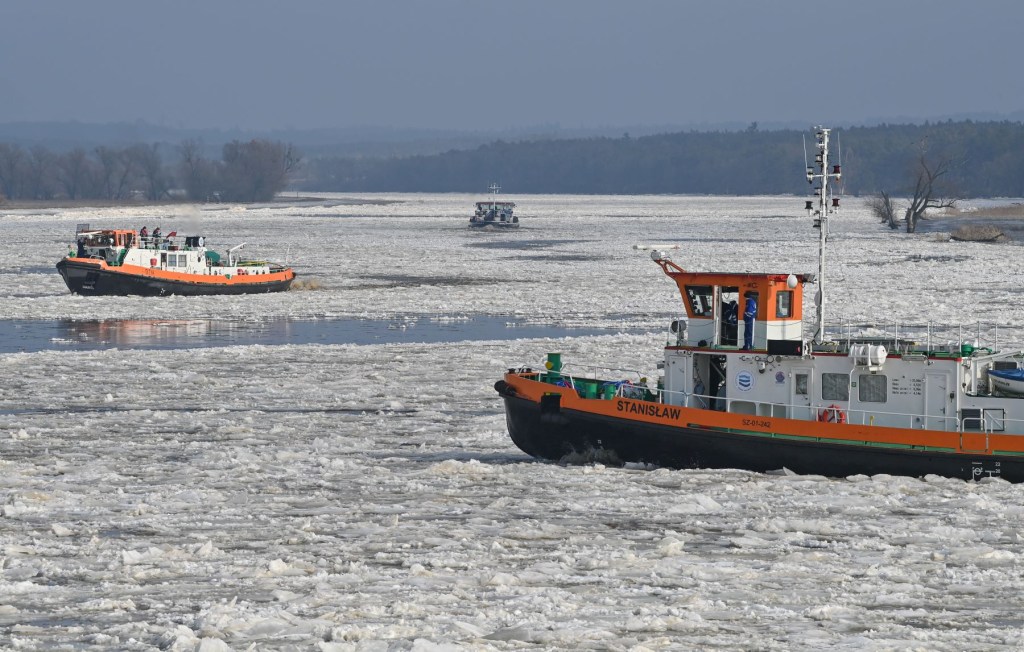 A pair of icebreaker boats sailing in frozen water during winter on the German-Polish border