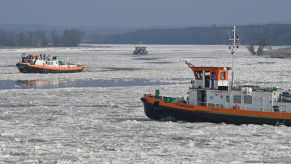 A pair of icebreaker boats sailing in frozen water during winter on the German-Polish border