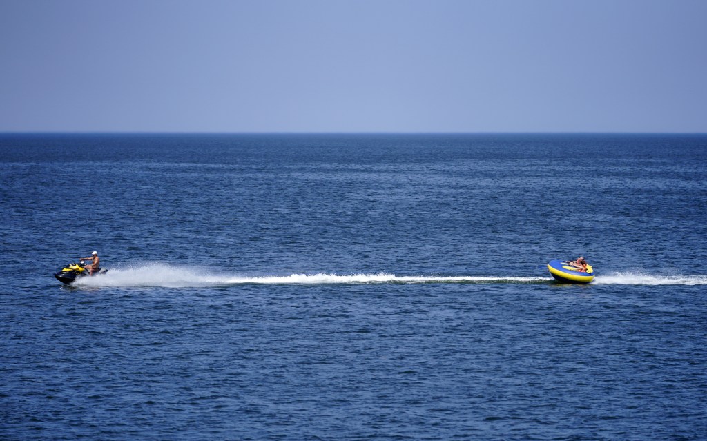 A jet ski tows people riding an inflatable tube in the Baltic Sea in June 2021