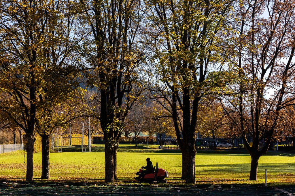 A man mowing the grass on a fall day 