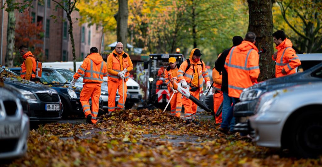 City employees removing leaves in a car parking lot in Hamburg, Germany