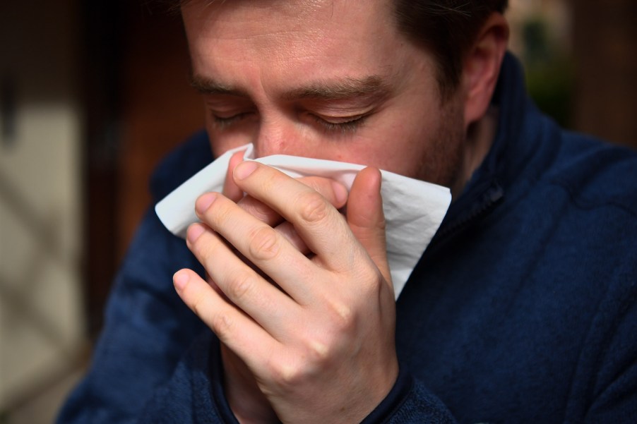 A man sneezing into a tissue