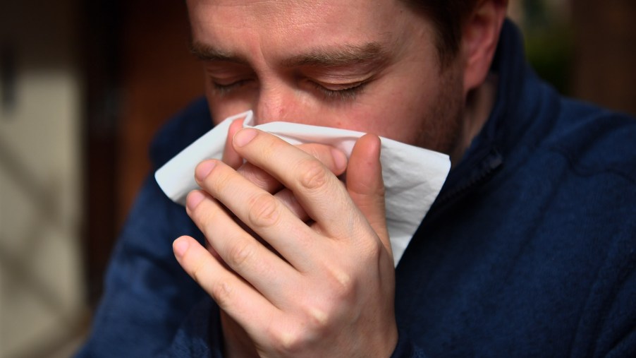 A man sneezing into a tissue