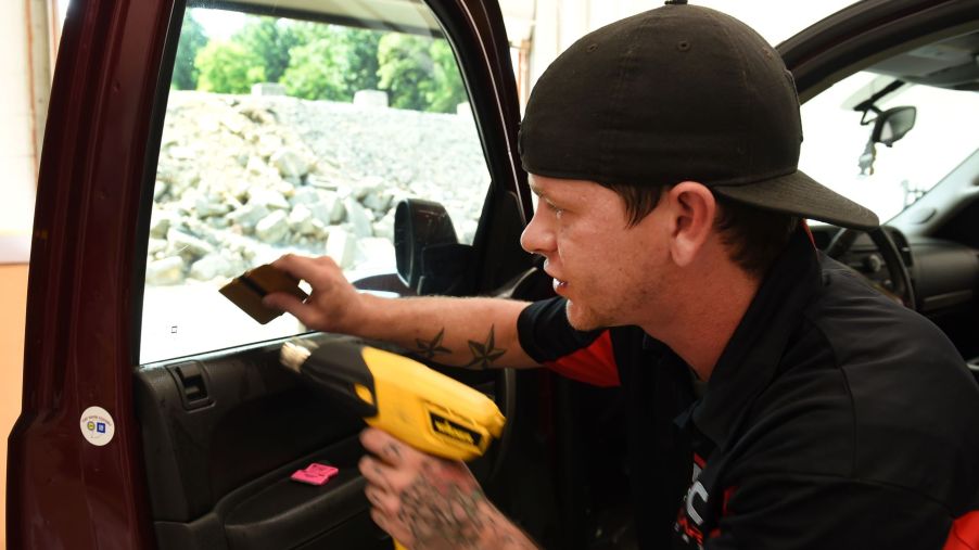 A man performing a window tinting service with a heat gun