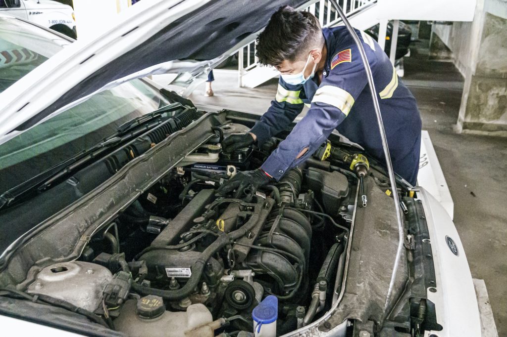  A mechanic does repair work on a car.