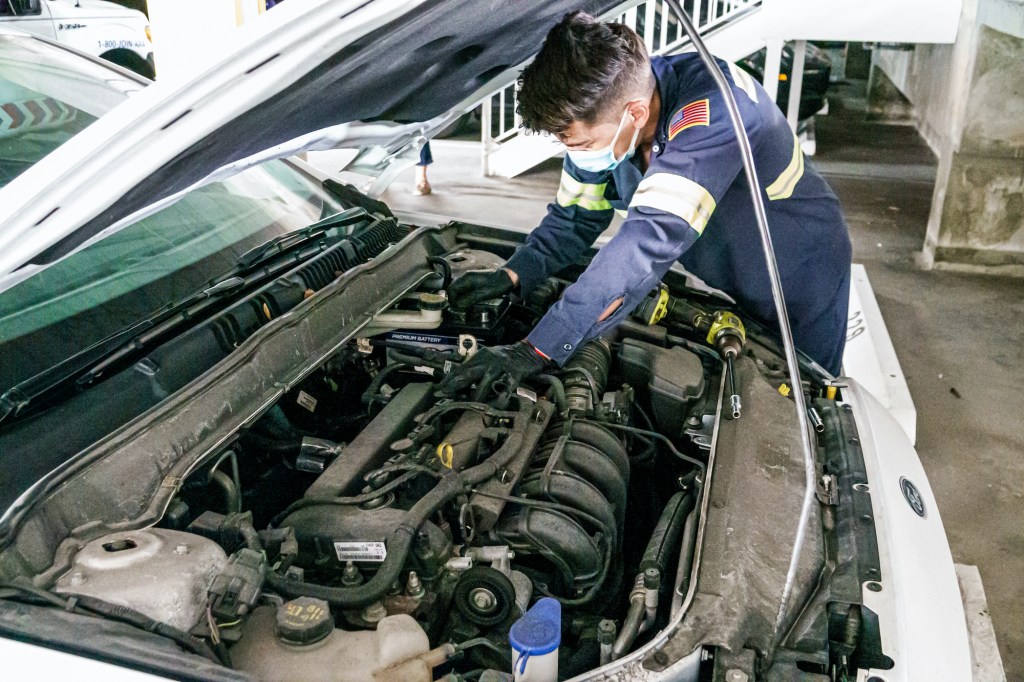 A mechanic does repair work on a car.