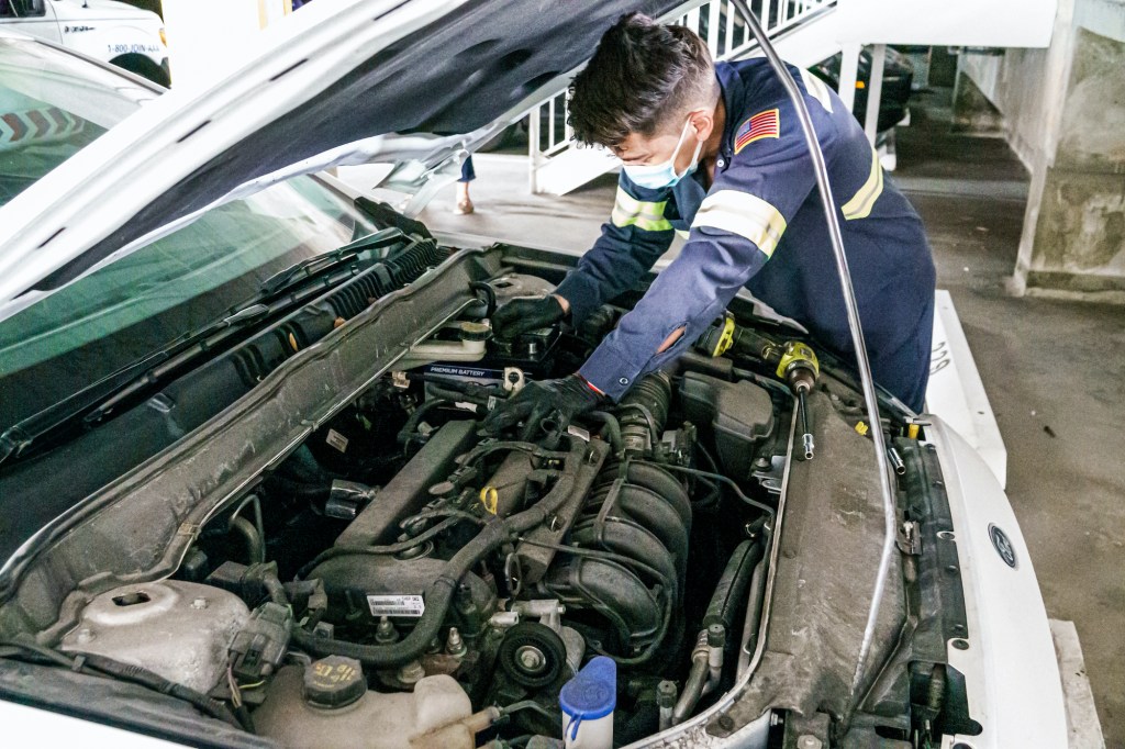  A mechanic does repair work on a car.