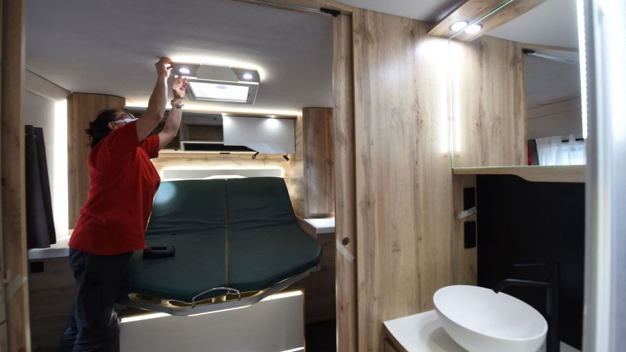 A woman checking the lights in a Le Voyageur motorhome bathroom in France