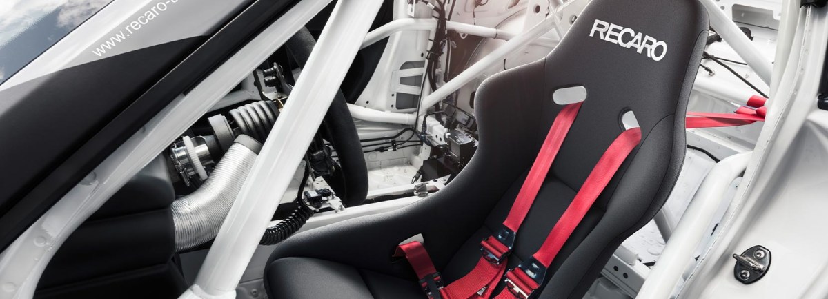 A black recaro racing seat in side of a white race car.