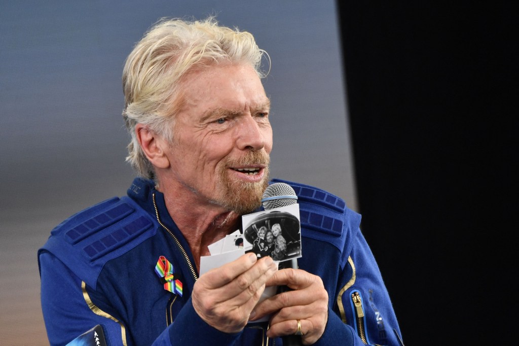 Sir Richard Branson holds up photos that he brought with him into space, as he speaks after flying into space aboard a Virgin Galactic vessel.
