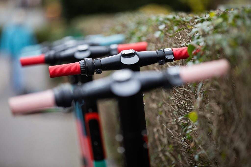 Some e-scooters are standing on a sidewalk 
