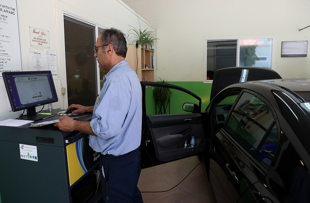 An automotive technician performing a smog check.