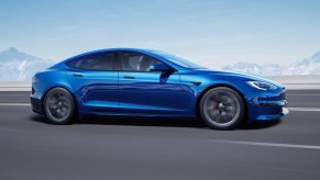 a blue Tesla Model S driving at speed on the road