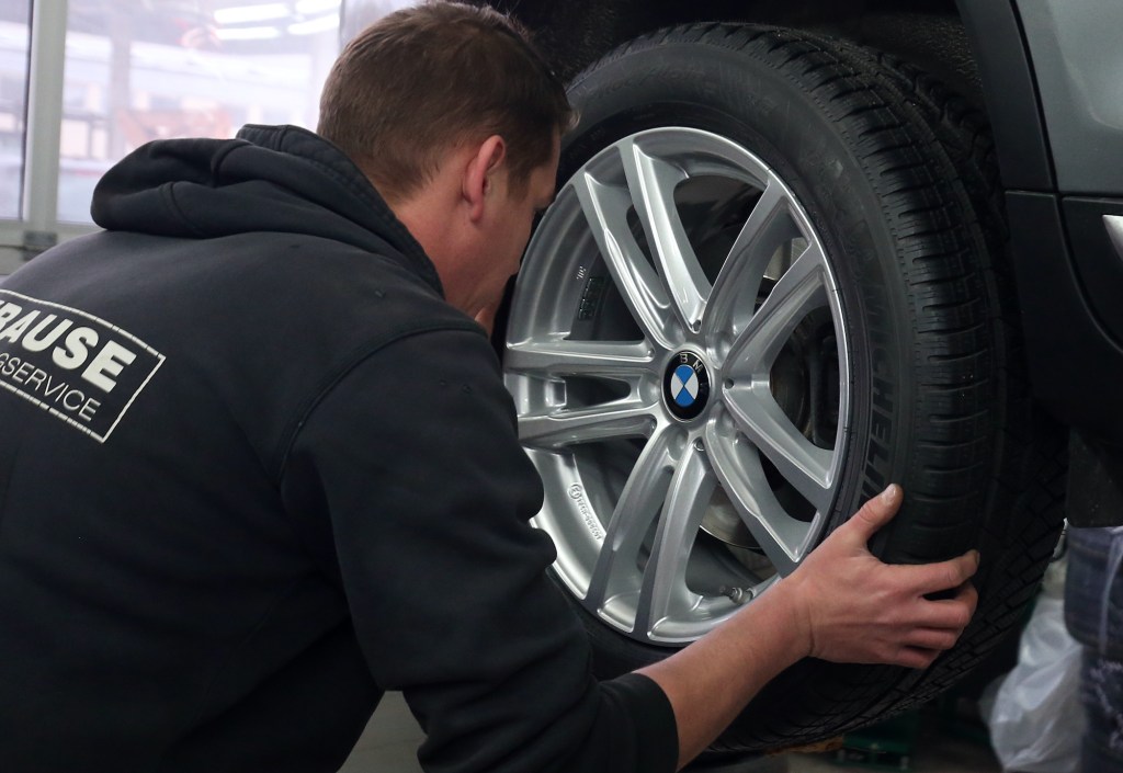 A mechanic at a car repair shop rotating tires.
