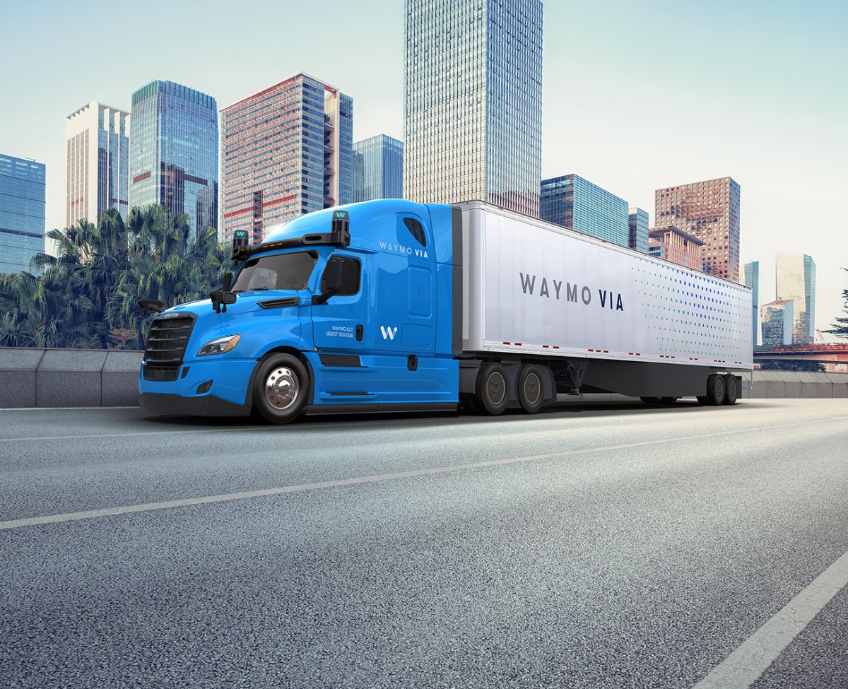 A Daimler Semi-truck with a blue cab and white container equipped with Waymo Driver technology.