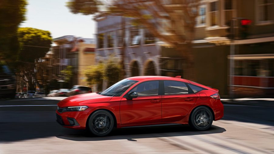 A red 2022 Honda Civic, which the 2022 Acura Integra is based on, hatchback shot in profile on a city street