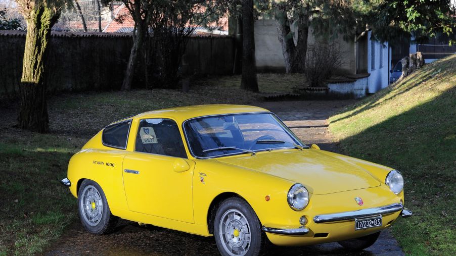 A yellow 1963 Fiat-Abarth Monomille GT parked on a grassy path
