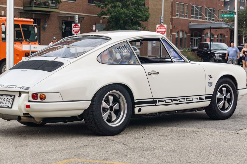The rear 3/4 view of a white-and-black 1967 Porsche 911R on the Checkeditout parking lot