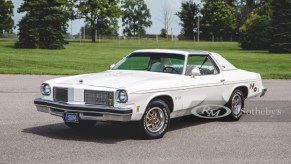 A white-and-gold 1975 Oldsmobile Cutlass Supreme Hurst/Olds W-30 in a parking lot