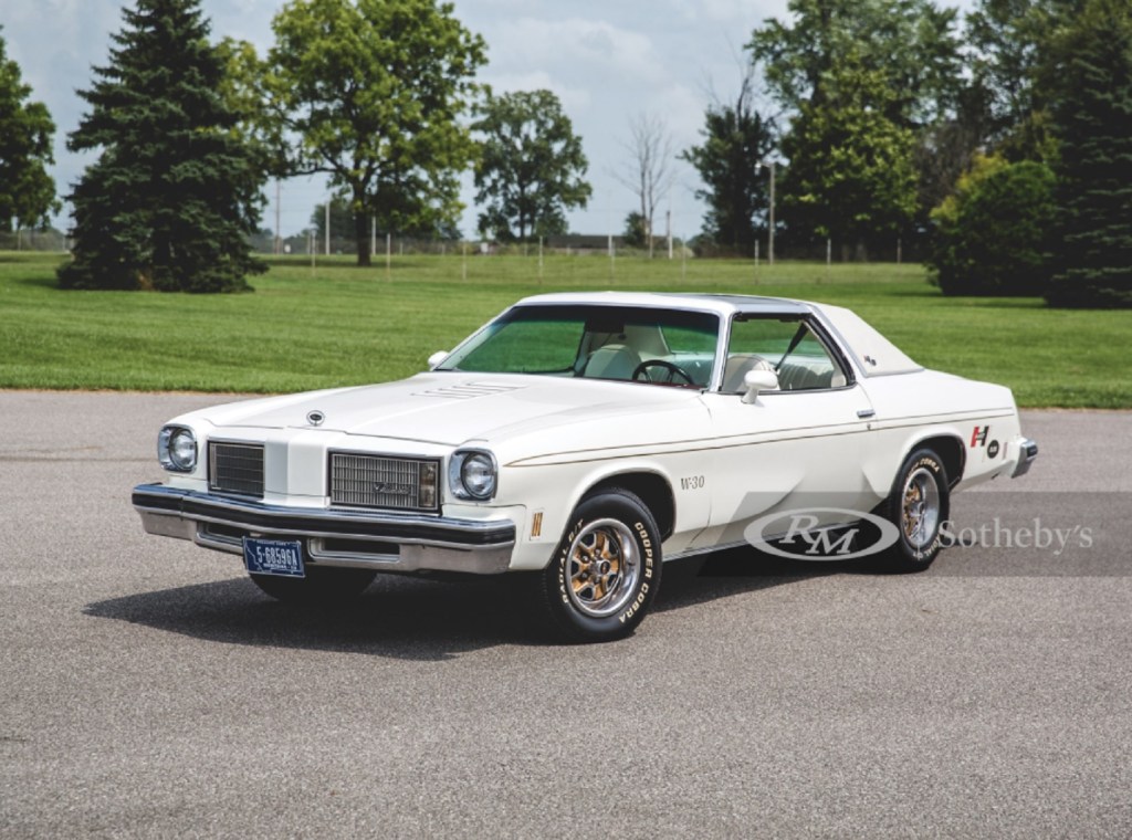 A white-and-gold 1975 Oldsmobile Cutlass Supreme Hurst/Olds W-30 in a parking lot