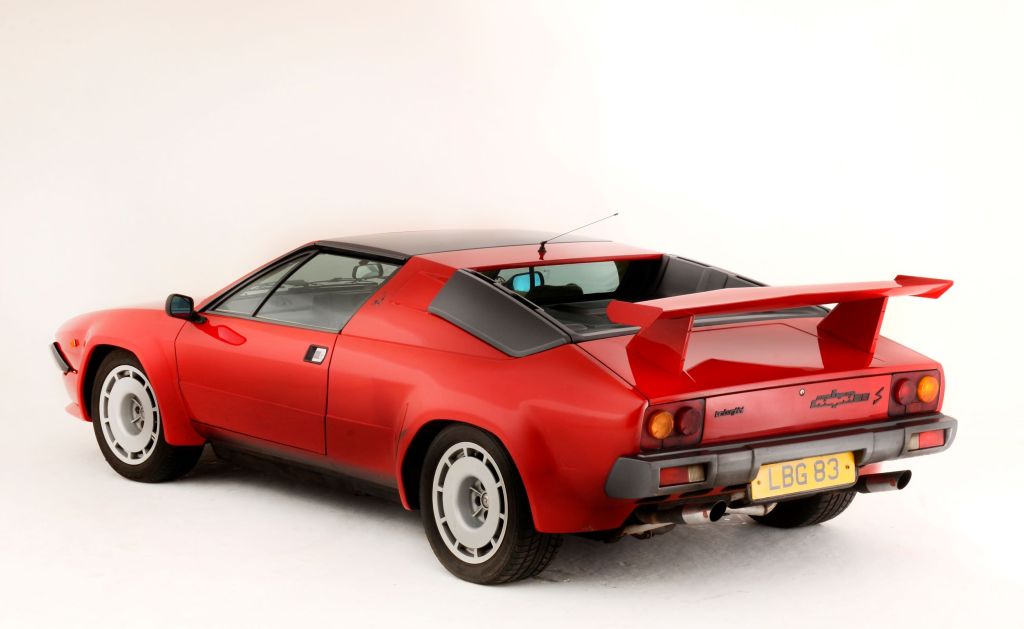 The rear 3/4 view of a red 1984 Lamborghini Jalpa S with a rear spoiler