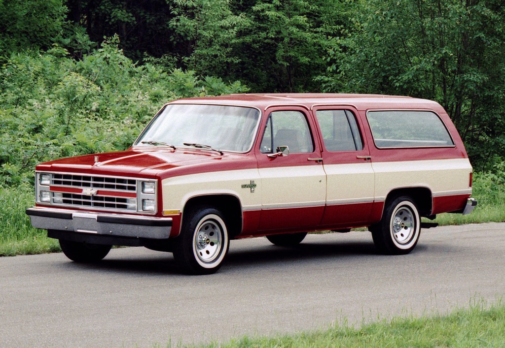 This is a vintage promo photo of a two-tone 1985 Chevrolet Suburban. In Cry Macho, Clint Eastwood's character drives a similar Chevrolet Suburban to Mexico | General Motors