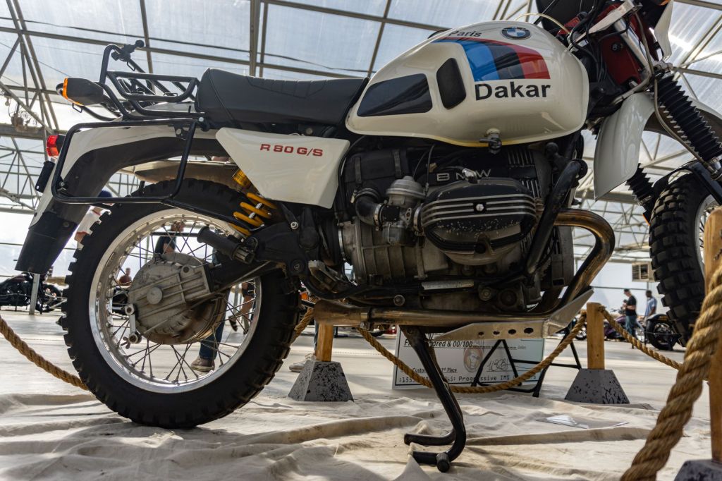 A low-angle side view of a white-black-red-and-blue 1987 BMW R80 G/S Paris Dakar's rear half and engine