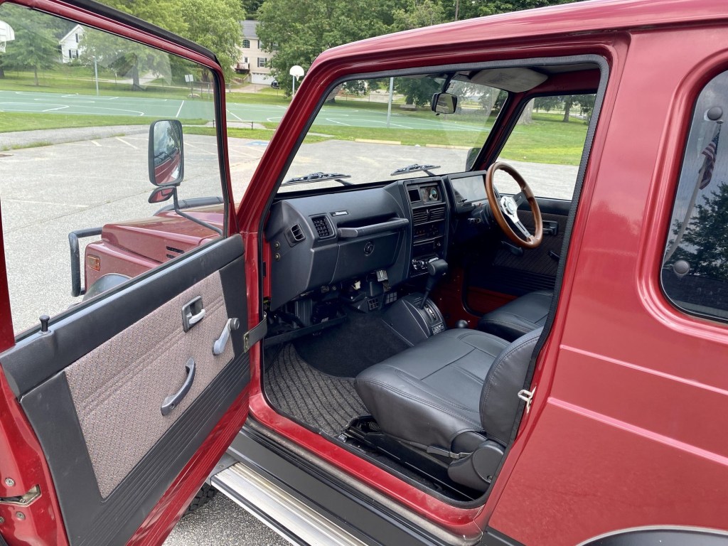 The side view of a red 1994 Suzuki Jimny Sierra 4x4's interior with leather seat covers
