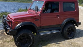 The side 3/4 view of a red 1994 Suzuki Jimny Sierra 4x4 by a lake