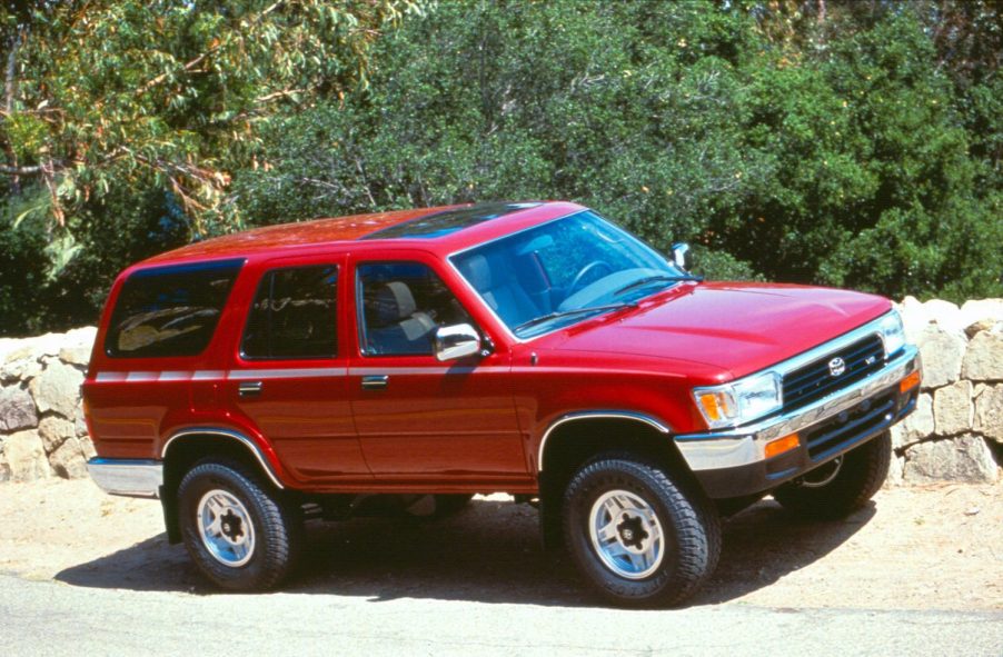 a red 1992 Toyota 4Runner driving on a rocky dirt trail in the mountains
