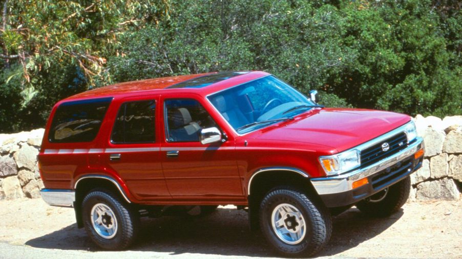 a red 1992 Toyota 4Runner driving on a rocky dirt trail in the mountains