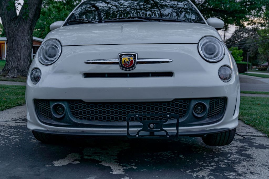 A white 2013 Fiat 500 Abarth with a black CravenSpeed Platypus front license plate holder