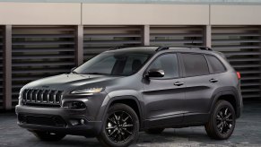 A gray 2015 Jeep Cherokee parked outside by a wall