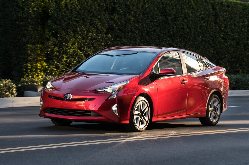 A red 2016 Toyota Prius Hybrid driving on a road