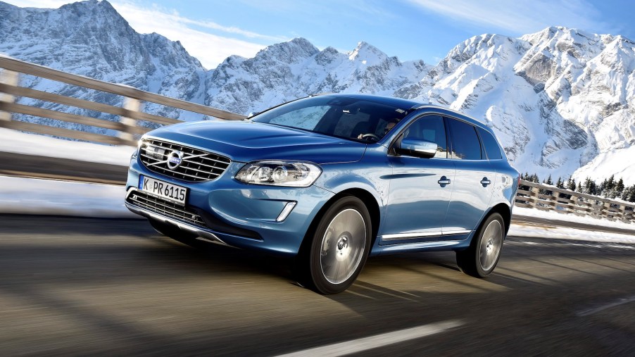 A 2017 Volvo XC60 T6 AWD luxury compact SUV travels on a highway past snow-capped mountains