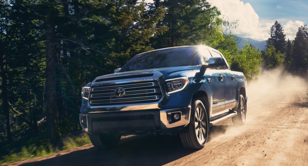 A blue Toyota Tundra pickup truck is driving on a dirt road. 