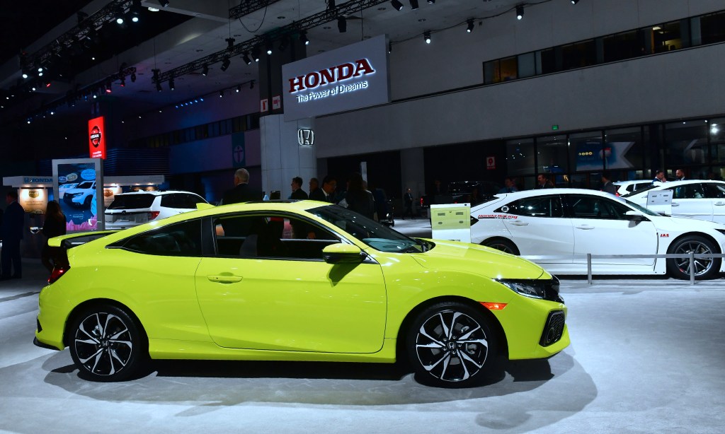 a yellow civic Si is on display at a car show